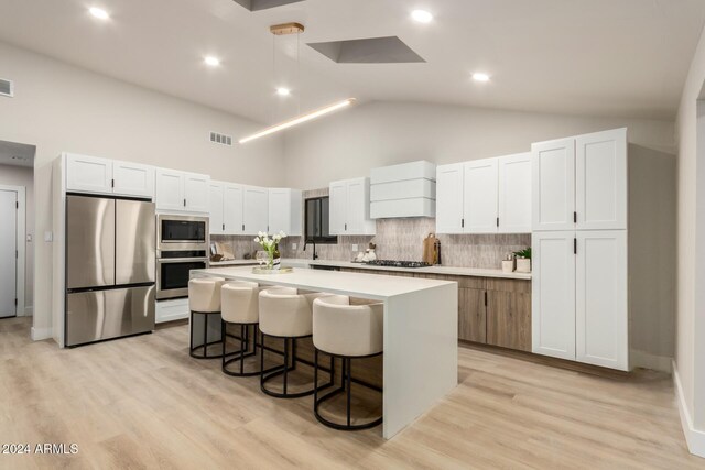 kitchen featuring stainless steel appliances, white cabinetry, and high vaulted ceiling