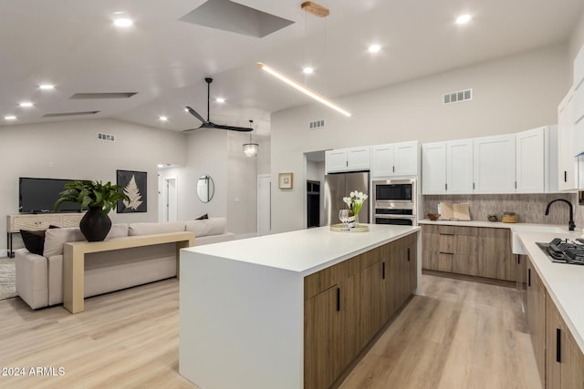 kitchen featuring backsplash, a spacious island, white cabinetry, and appliances with stainless steel finishes