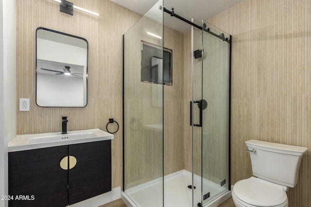 bathroom with toilet, vanity, ceiling fan, and a shower with door