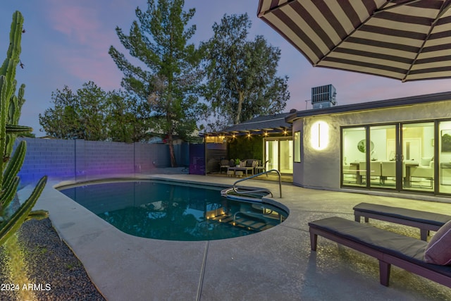 pool at dusk featuring a patio area and central air condition unit