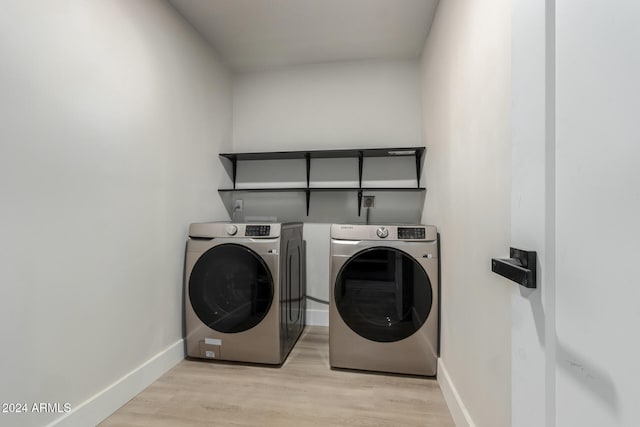 washroom with washing machine and dryer and light hardwood / wood-style floors