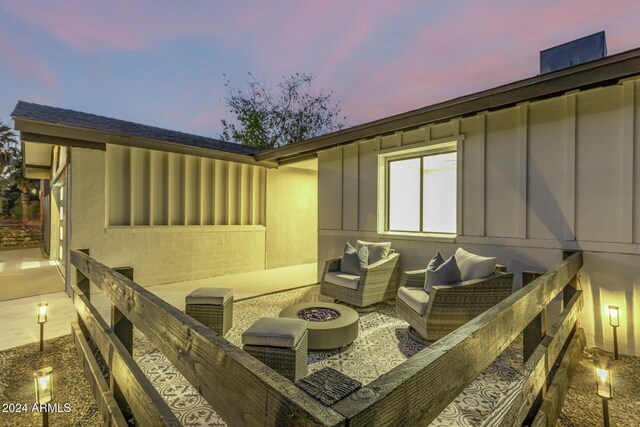 property exterior at dusk featuring an outdoor living space with a fire pit and a patio area