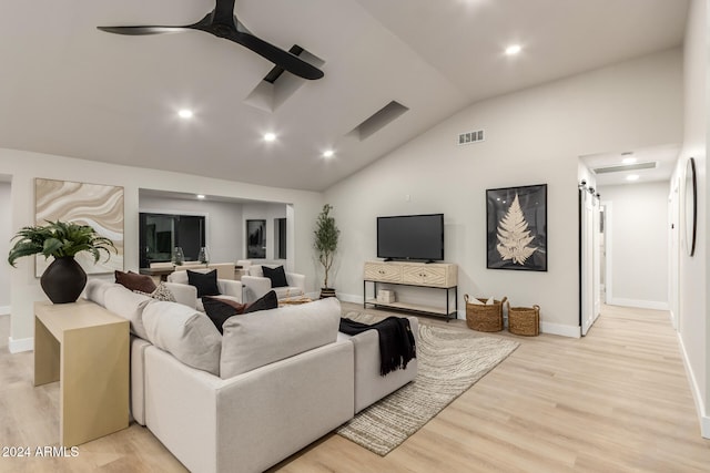 living room with lofted ceiling, a barn door, and light wood-type flooring