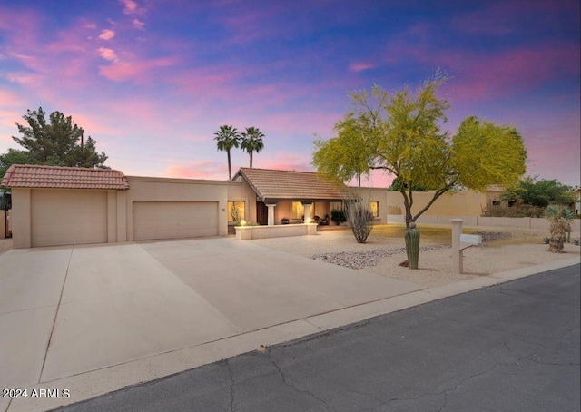 view of front of home with a garage, driveway, a tiled roof, and stucco siding