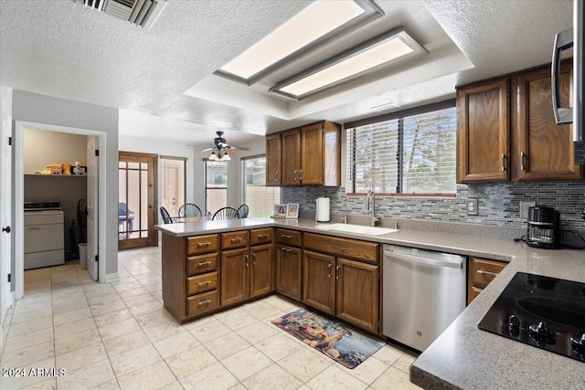 kitchen featuring light countertops, decorative backsplash, appliances with stainless steel finishes, a sink, and a peninsula