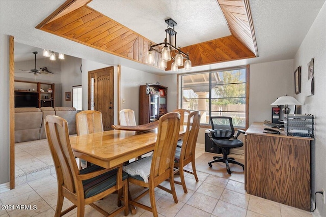 dining space featuring a tray ceiling, vaulted ceiling, a textured ceiling, and ceiling fan with notable chandelier