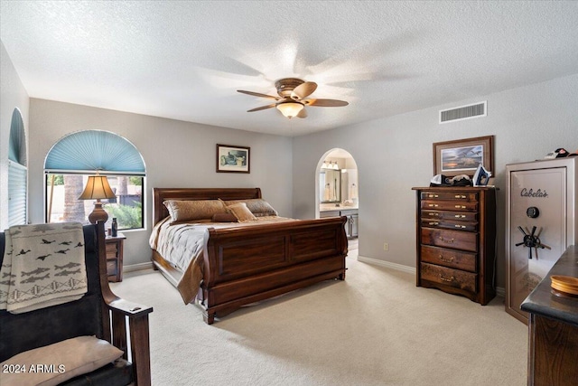 bedroom featuring arched walkways, visible vents, light carpet, a textured ceiling, and baseboards