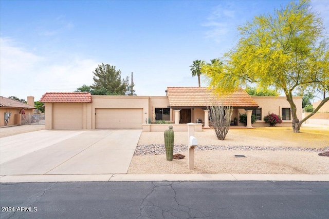 view of front of property with a tiled roof, concrete driveway, an attached garage, and stucco siding