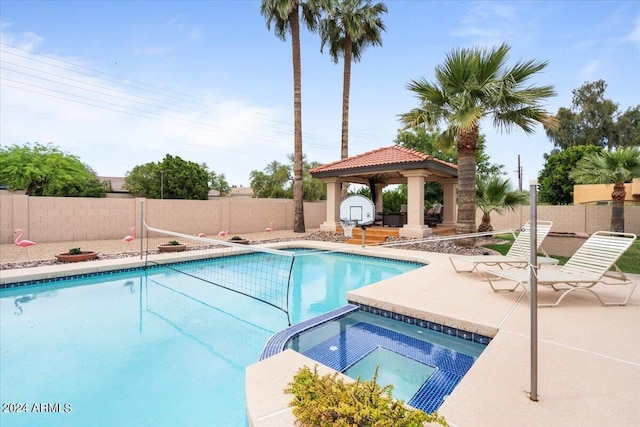 view of pool featuring a pool with connected hot tub, a fenced backyard, a patio, and a gazebo