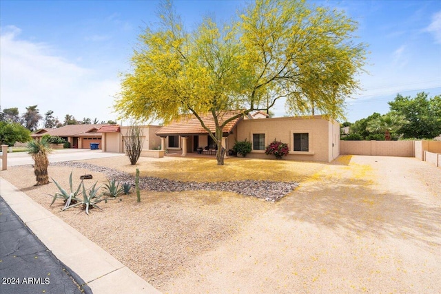 view of front of property featuring stucco siding, driveway, and fence