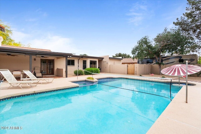 view of swimming pool featuring ceiling fan, a patio area, fence, and a pool with connected hot tub