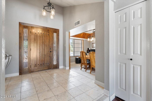 entrance foyer featuring visible vents, a notable chandelier, and baseboards