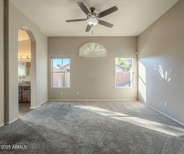 carpeted spare room featuring plenty of natural light and ceiling fan