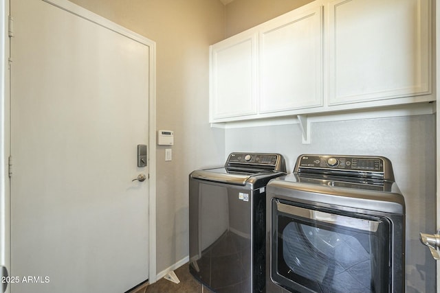 clothes washing area featuring cabinets, washer and dryer, and dark tile patterned floors