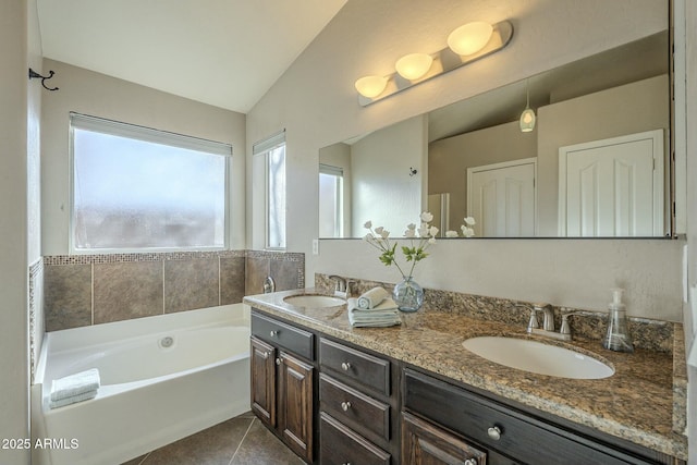 bathroom featuring lofted ceiling, a tub to relax in, tile patterned flooring, and vanity