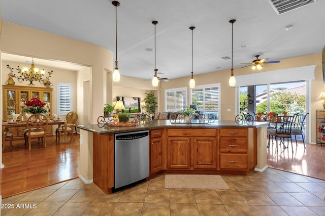kitchen featuring brown cabinets, light tile patterned floors, visible vents, stainless steel dishwasher, and ceiling fan with notable chandelier