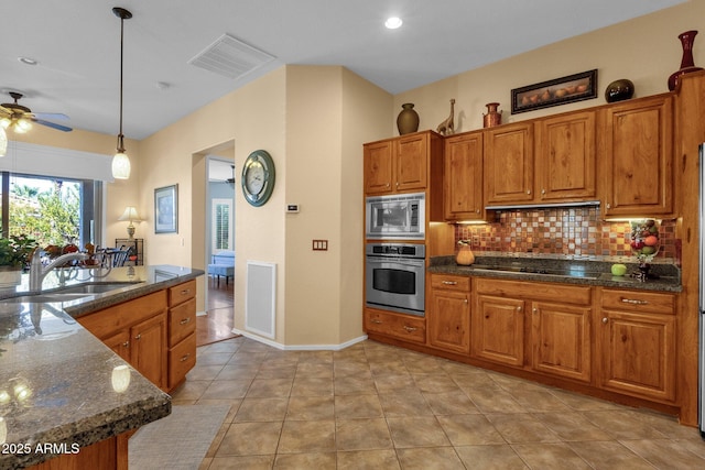 kitchen featuring appliances with stainless steel finishes, visible vents, tasteful backsplash, and brown cabinetry