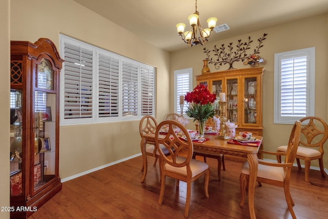 dining room featuring visible vents, a healthy amount of sunlight, a notable chandelier, and wood-type flooring