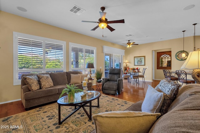 living room featuring baseboards, visible vents, wood finished floors, and ceiling fan