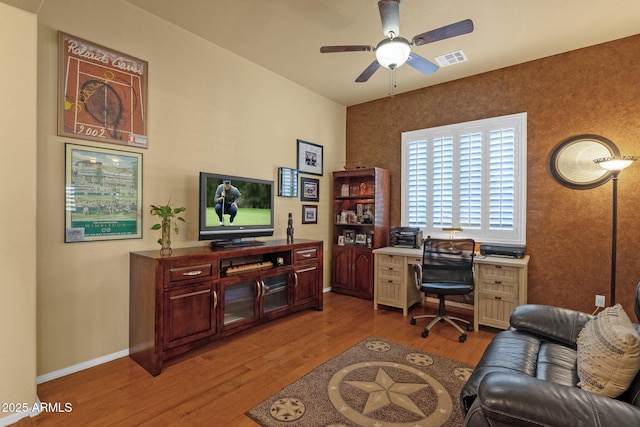 home office with wood finished floors, visible vents, a ceiling fan, and baseboards