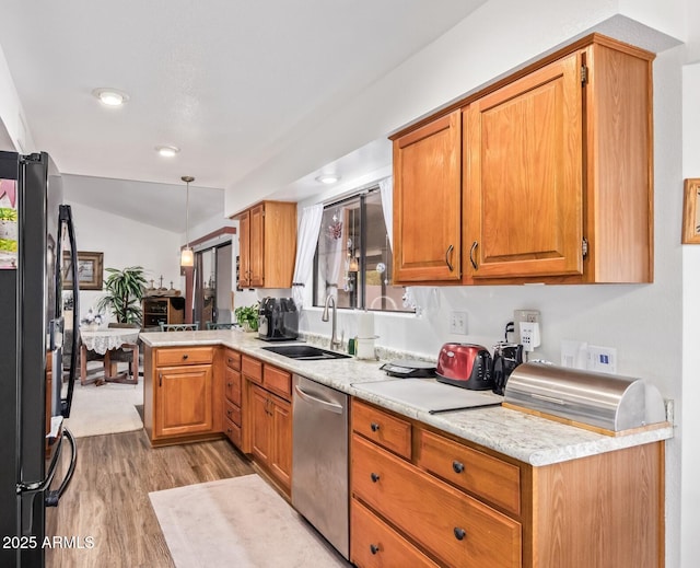 kitchen featuring dishwasher, freestanding refrigerator, a peninsula, light countertops, and a sink