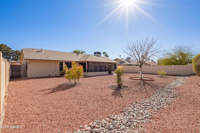 back of house featuring a sunroom, a fenced backyard, and stucco siding