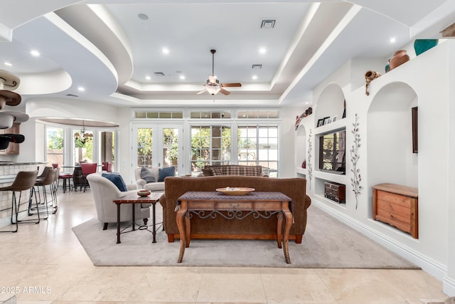 living room with a tray ceiling and ceiling fan