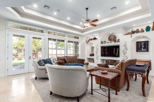 tiled living room with french doors, a healthy amount of sunlight, and a tray ceiling