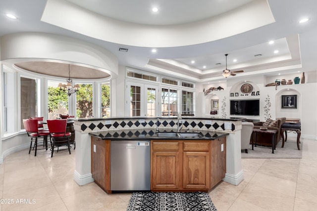 kitchen with sink, tasteful backsplash, dishwasher, a raised ceiling, and a kitchen island