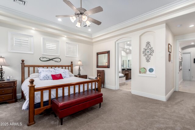 bedroom with crown molding, ceiling fan, connected bathroom, a tray ceiling, and light colored carpet