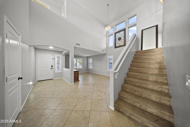 9719 W Heber Rd, Tolleson, AZ 85353 - entryway with visible vents, a towering ceiling, arched walkways, light tile patterned floors, and stairs