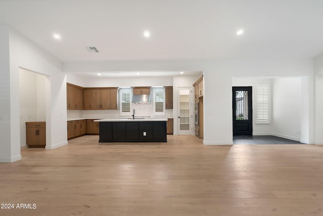 kitchen featuring light countertops, visible vents, open floor plan, light wood-type flooring, and under cabinet range hood