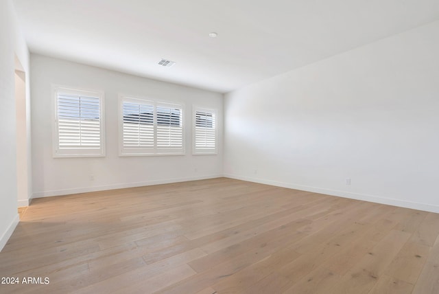 spare room featuring visible vents, light wood-style flooring, and baseboards