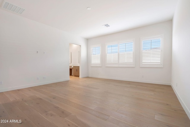 empty room with visible vents, light wood-style flooring, and baseboards