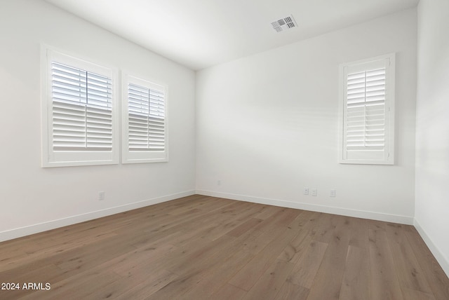 empty room with light wood-type flooring, visible vents, and baseboards