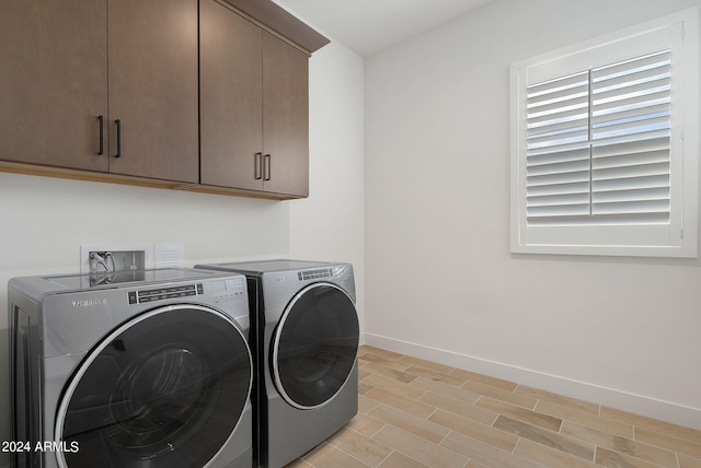 washroom featuring washing machine and clothes dryer, cabinet space, and baseboards