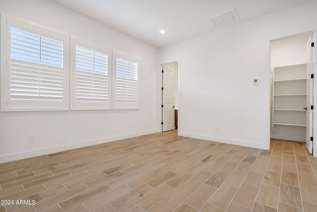 spare room featuring light wood-style floors, recessed lighting, visible vents, and baseboards