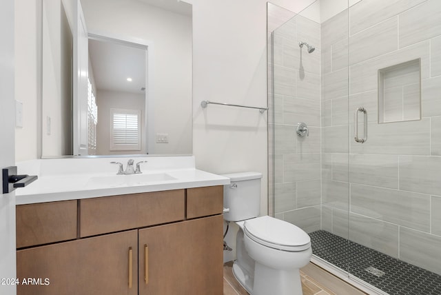 full bathroom featuring a stall shower, vanity, and toilet