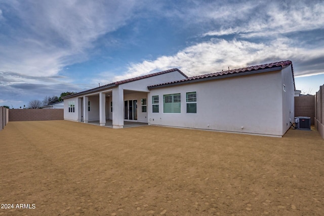 back of house with a fenced backyard, central AC, a lawn, stucco siding, and a patio area