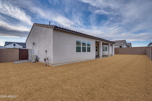 back of property featuring a tile roof, central air condition unit, a fenced backyard, and stucco siding