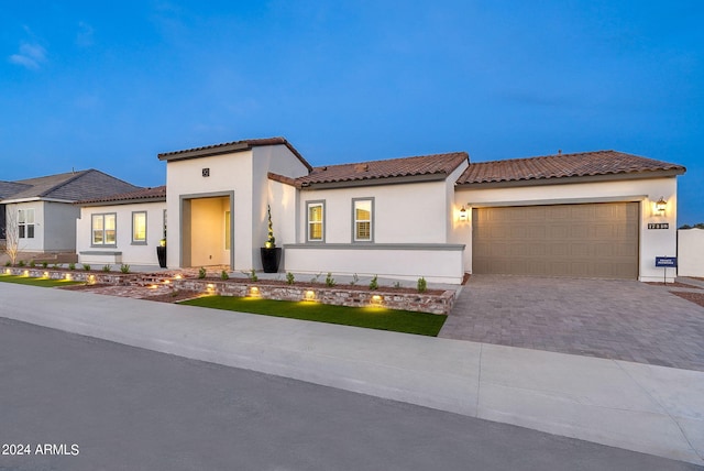 mediterranean / spanish-style house with a garage, a tiled roof, driveway, and stucco siding