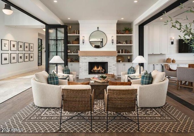 living area with recessed lighting, a fireplace, wood finished floors, baseboards, and built in features