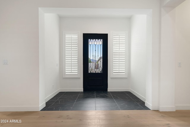 foyer entrance with marble finish floor and baseboards