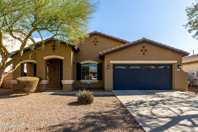 mediterranean / spanish-style house featuring driveway, an attached garage, a tiled roof, and stucco siding