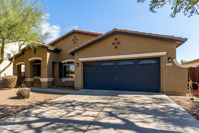 mediterranean / spanish-style home featuring an attached garage, a tiled roof, concrete driveway, and stucco siding