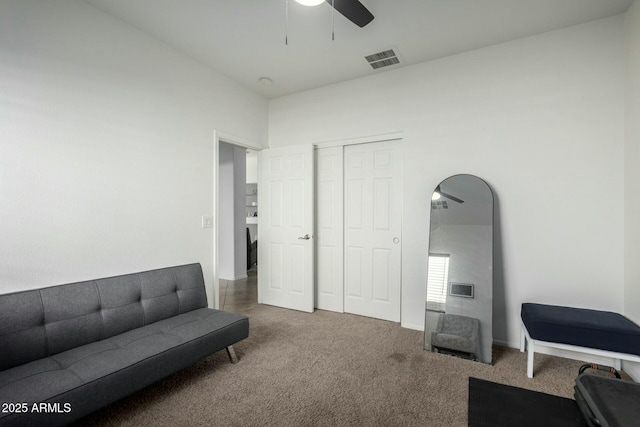 living area with a ceiling fan, visible vents, and dark carpet