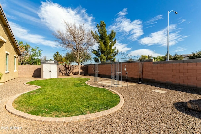 view of yard with a storage shed, a fenced backyard, and an outbuilding