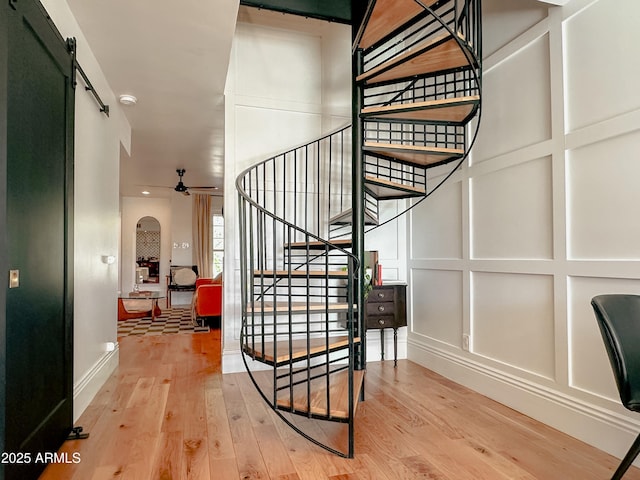 stairs featuring hardwood / wood-style flooring, a barn door, and ceiling fan