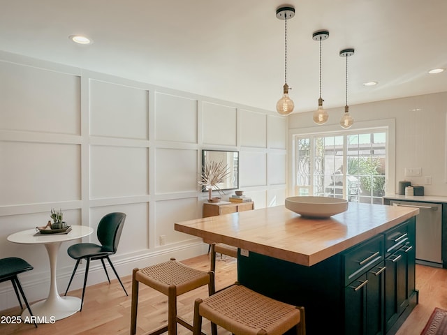 kitchen featuring butcher block countertops, decorative light fixtures, dishwasher, a center island, and light wood-type flooring