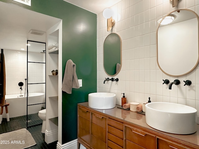 bathroom featuring tile walls, a bathtub, vanity, toilet, and tile patterned floors